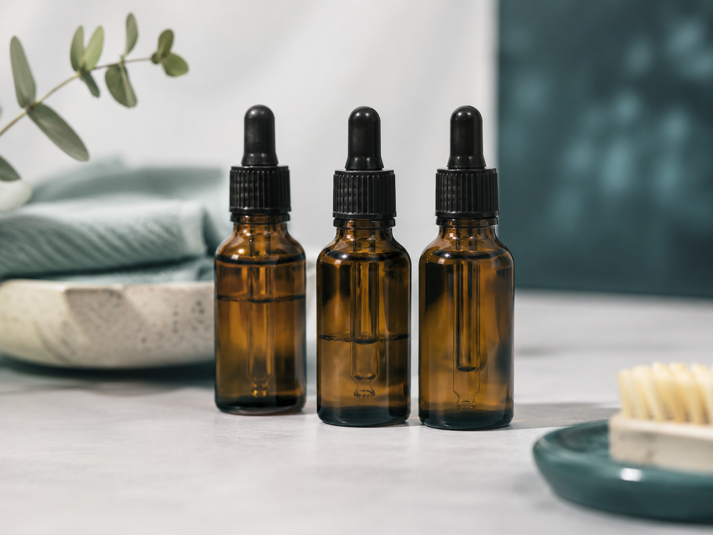 Honest neutral side-by-side concept image of three unlabeled amber dropper bottles standing together to convey a white-l
